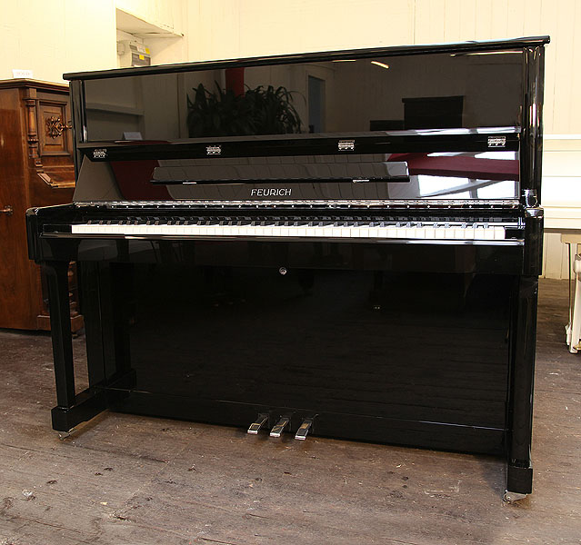 Brand new, Feurich Model 122 upright piano with a black case and chrome fittings. Piano has an eighty-eight note keyboard and three pedals 