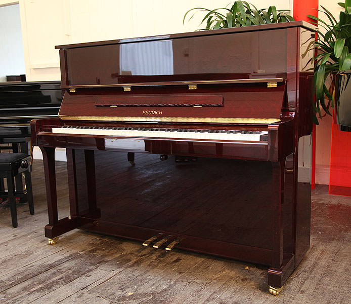 Brand new, Feurich Model 122 upright piano with a  mahogany case and brass fittings. Piano has an eighty-eight note keyboard and three pedals 