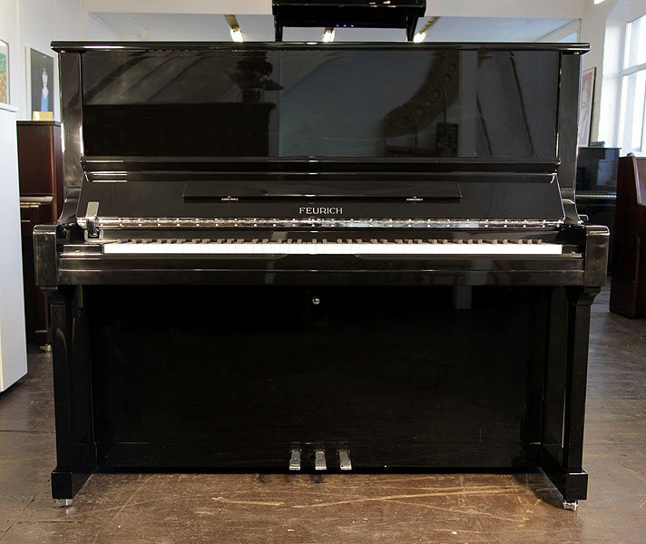 A brand new, Feurich Model 133 Concert upright piano with a black case and brass fittings Piano has an eighty-eight note keyboard and three pedals