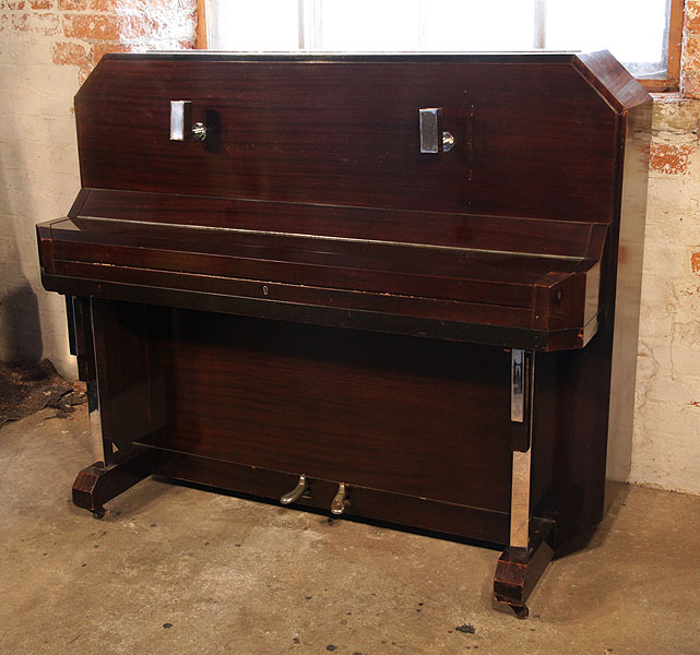 Barker upright piano with an Art Deco style, mahogany case. Cabinet features strong angular styling and chrome fittings. Piano has an eighty-five note keyboard and a two-pedal piano lyre.
