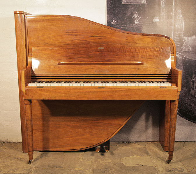 A 1953, Rippen upright grand piano with an Art-Deco style walnut case. Cabinet features telescopic style legs. The cabinet follows the sinuous line of the internal grand piano frame. Piano has an eighty-eight note keyboard and two pedals. 