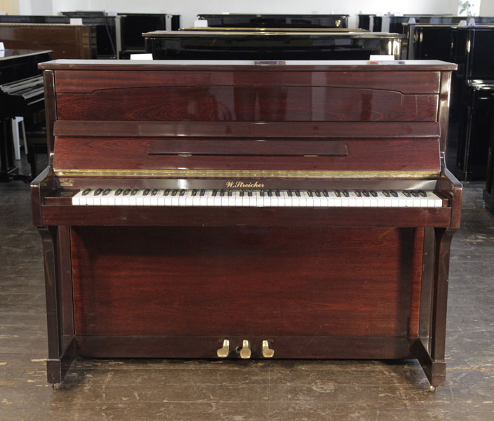 A Streicher upright piano with a mahogany case. Piano has an eighty-eight note keyboard and and three pedals