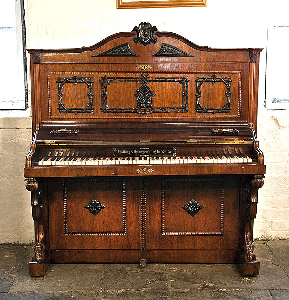 A Holling Spangenberg upright piano for sale with a rosewood case, candlestick holders and claw foot legs. Piano features carvings of intertwined wood branches. Piano has an eighty-five keyboard and one pedal.