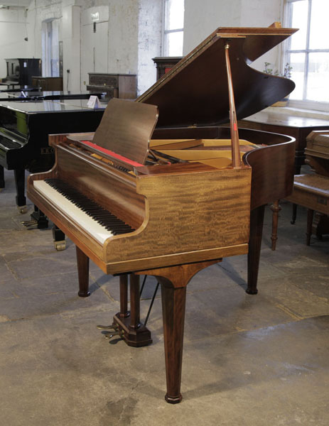 A pre-owned, 1933, Rogers baby grand piano with a fiddleback mahogany case and octagonal, faceted legs. Piano has an eighty-eight note keyboard and a two-pedal lyre.
