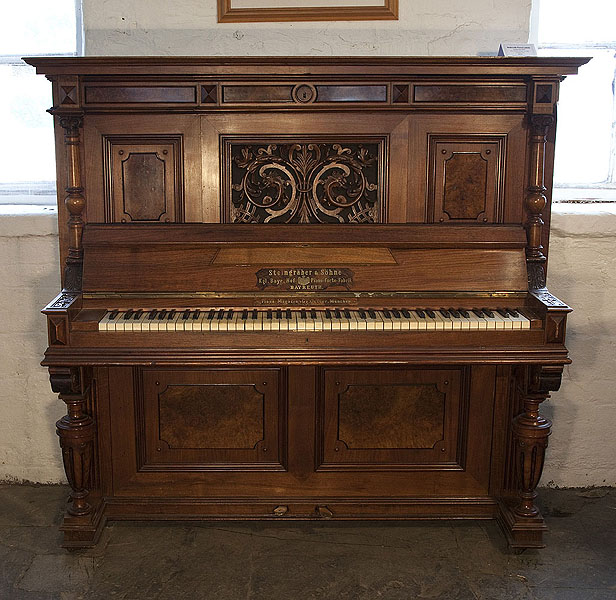 An 1898, Steingraeber upright piano with a Neoclassical style, carved walnut case and cup and cover legs. Cabinet features a front panel carved with acanthus and dragon heads in high relief. Piano has an eighty-five note keyboard and two pedals