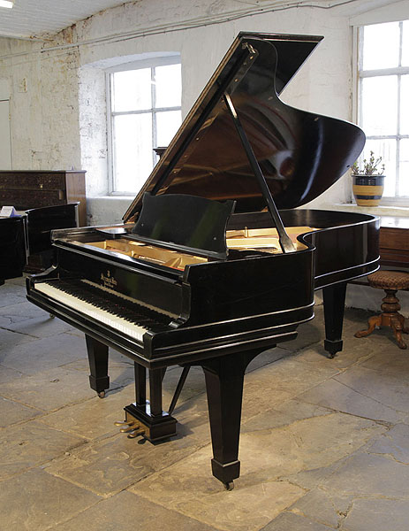 A 1902, Steinway Model B grand piano with a black case and spade legs. Piano has a three-pedal lyre and an eighty-eight note keyboard.