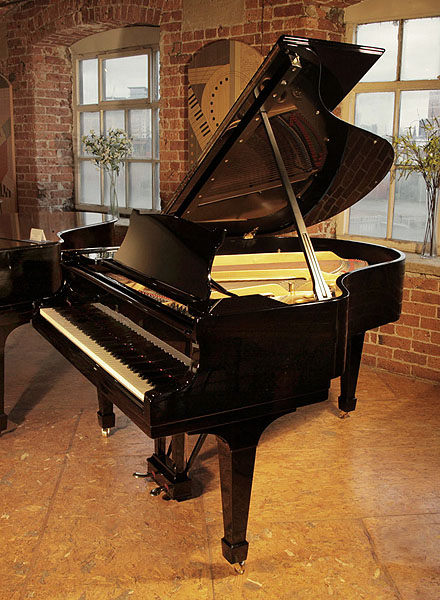 A 1936, Steinway Model M grand piano with a black case and spade legs. Piano has an eighty-eight note keyboard and a two-pedal lyre. 