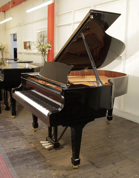 A brand new, Toyama TC-187 grand piano for sale with a black case and spade legs. Piano features a slow fall mechanism on the keyboard lid. Piano has an eighty-eight note keyboard and a three-pedal lyre.