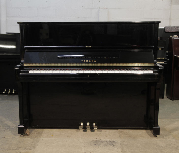 A 1990, Yamaha U1 upright piano with a black case and polyester finish. Piano has an eighty-eight note keyboard and three pedals.