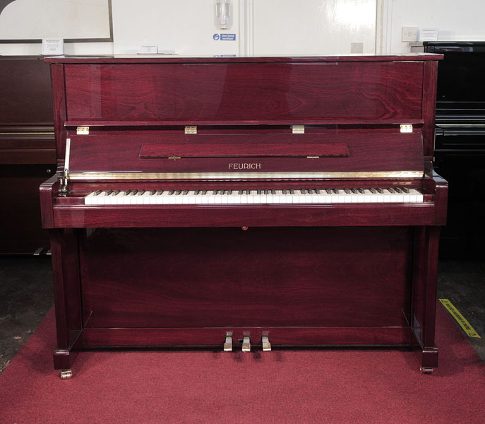 Brand new, Feurich Model 122 upright piano with a mahogany case and brass fittings. Piano has an eighty-eight note keyboard and three pedals..