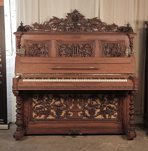 Renaissance style, 1871, Biese Hof upright piano in polished, oak with barley sugar legs. Entire cabinet features ornately carved, openwork panels in high relief featuring naturalistic depictions of intertwining vines, grapes and foliage with a central lyre motif.  Piano has an eighty-five note keyboard and two pedals.