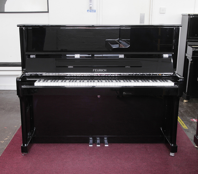 Brand new, Feurich Model 122 upright piano with a black case and chrome fittings. Piano has an eighty-eight note keyboard and three pedals.