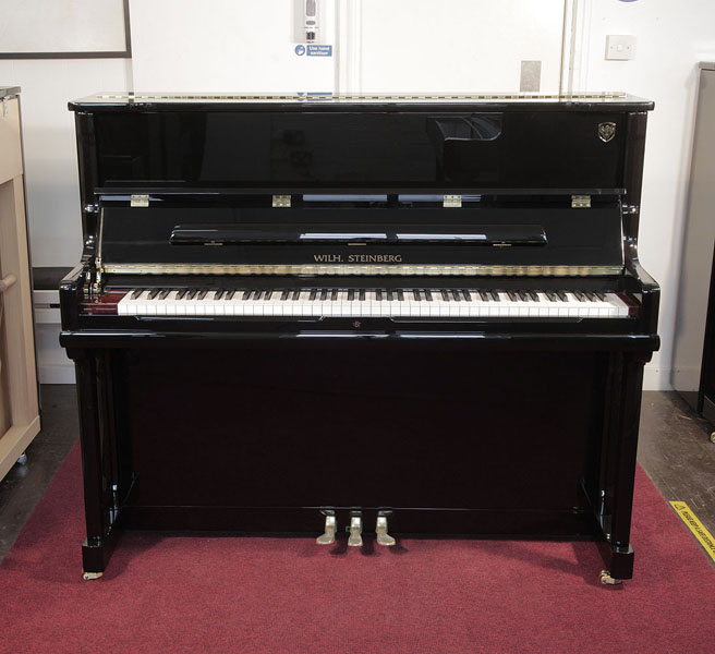 Brand new, Wilh. Steinberg Model AT-K23 upright piano with a black case and brass fittings. Piano lid features a slow fall mechanism. Piano has an eighty-eight note keyboard and three pedals. 