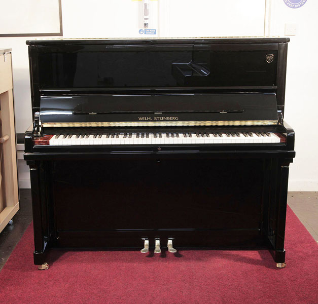 Brand new, Wilh. Steinberg Model AT-K30 upright piano with a black case and brass fittings. Piano features a walnut key block and slow fall mechanism. Piano has an eighty-eight note keyboard and three pedals.