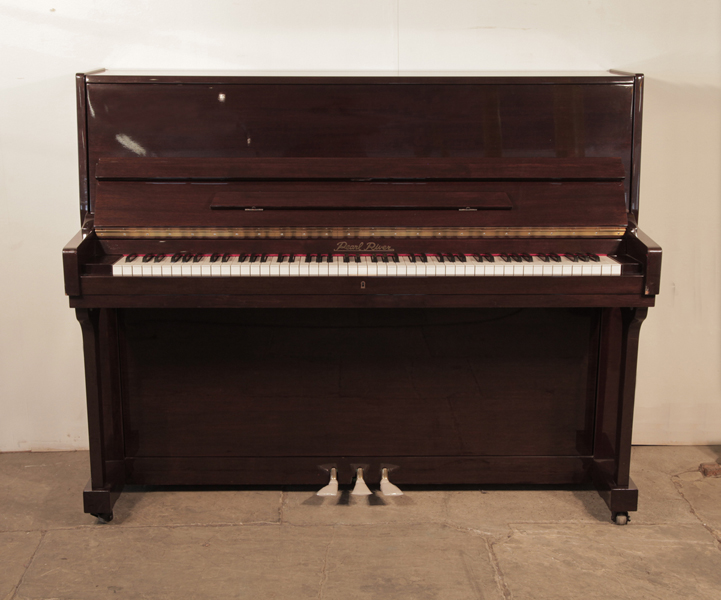 Pre-owned, 2001, Pearl River upright piano with a mahogany case and polyester finish. Piano has an eighty-eight note keyboard and and three pedals.