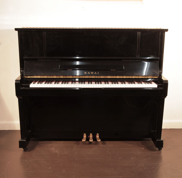 Reconditioned, 1991, Kawai BS-25 upright piano with a black case and brass fittings. Piano has an eighty-eight note keyboard and three pedals.  