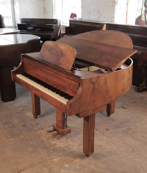 An Art Deco style Strohmenger baby grand piano with a walnut case. Piano legs amd lyre feature strong geometric styling