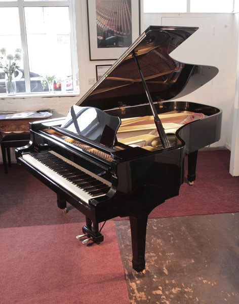 Reconditioned, 1980,  Yamaha C7 grand piano with a black case and spade legs. Piano has an eighty-eight note keyboard and a two-pedal lyre. 