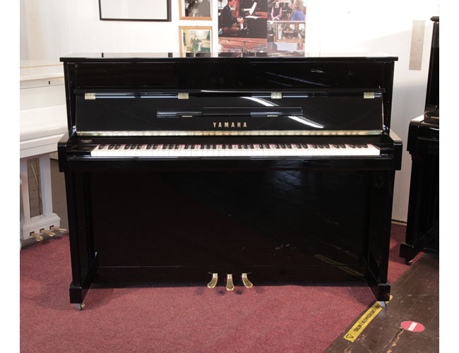Pre-owned, 2022, Yamaha b2e PE upright piano with a gloss black case and brass fittings. Piano has an eighty-eight note keyboard and three pedals.  Condition as new