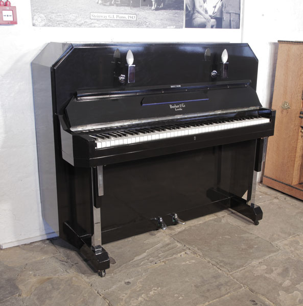 Barker upright piano with an Art Deco style, black case. Cabinet features strong angular styling and chrome fittings. Piano has an eighty-five note keyboard and  two pedals.