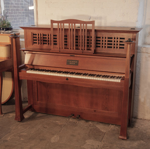 Arts and Crafts style, 1905, Bechstein model 9 upright piano with an oak case, ornate iron hinges and large sculptural candlesticks. Designed by Walter Cave. Piano has an eighty-five note keyboard and two pedals. 