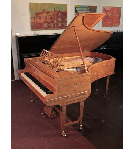 A 1911, Bluthner grand piano with a quarter cut, satinwood case with boxwood stringing inlay. Entire cabinet inlaid with swagged bellflowers, secured with bows. Piano has gate legs attached with a cross stretcher. Piano has an eighty-eight note keyboard and a two-pedal lyre 