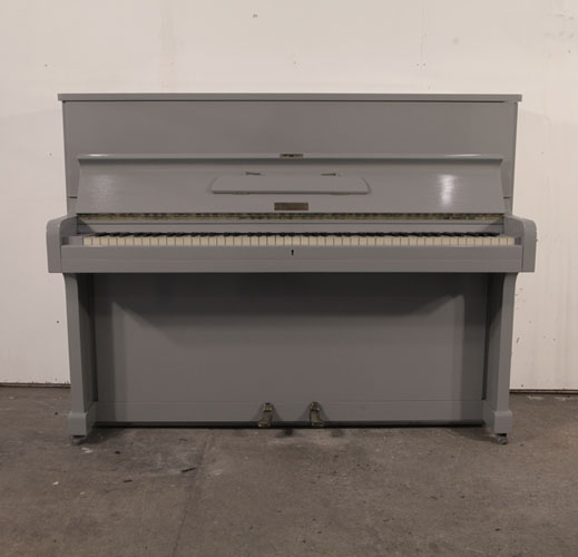 A 1953, Broadwood upright piano with a grey gloss cabinet and brass fittings. Piano has an eighty-eight note keyboard and two pedals. 