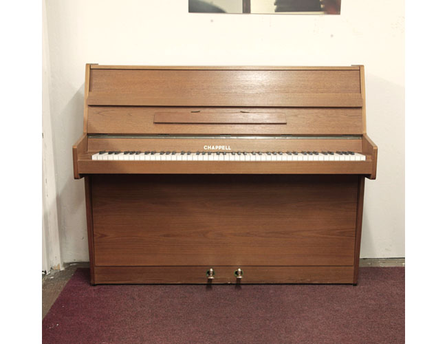 British-made, Chappell upright piano with a walnut case and Schwander action. Piano has an eighty-eight note keyboard and two pedals 