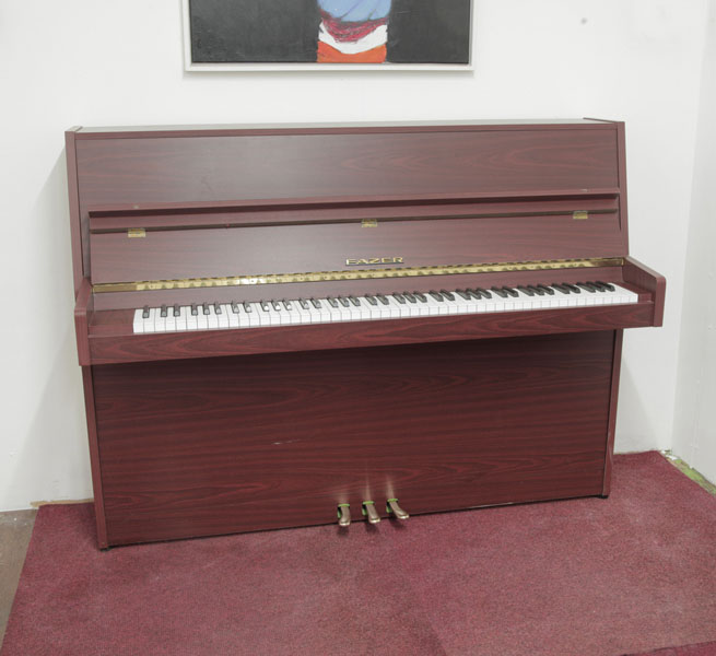 A 1977, Fazer upright piano with a mahogany case. Piano has an eighty-eight note keyboard and three pedals.