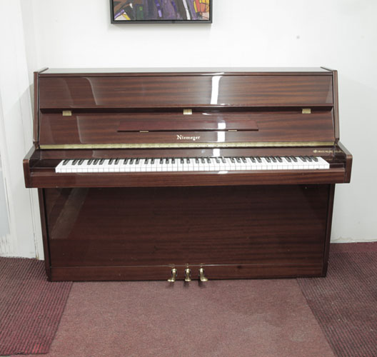 Niemeyer upright piano with a mahogany gloss case. Piano has an eighty-eight note keyboard and three pedals. 