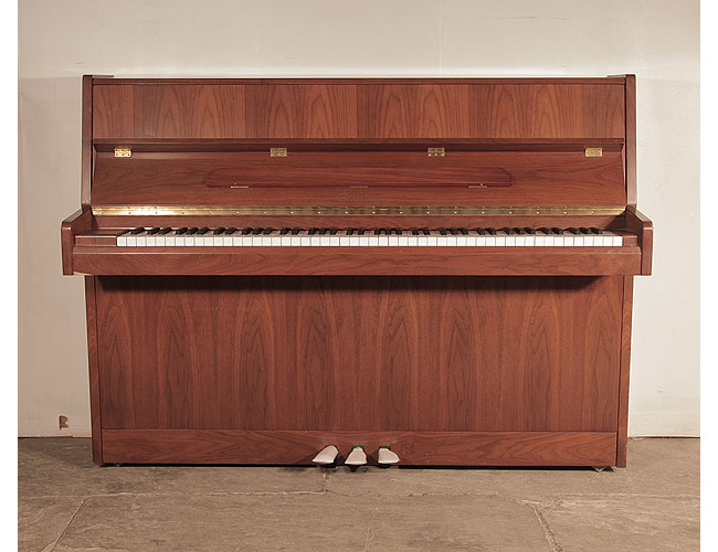 Ottostein SU-108P upright piano with a crown-cut walnut case. Piano has an eighty-eight note keyboard and three pedals. 